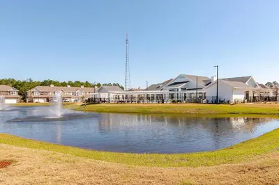a pond with a fountain in front of houses at King Condo Panama City Beach All Amenities Resort in Panama City Beach