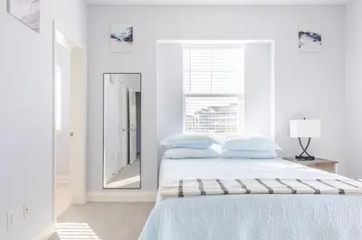 a white bedroom with a bed and a mirror at King Condo Panama City Beach All Amenities Resort in Panama City Beach