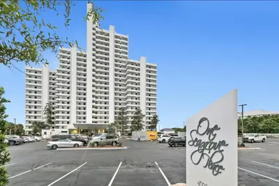 a large white building with cars parked in a parking lot at Book Me Baby! The One at One Seagrove Place in Seagrove Beach