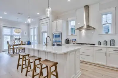 a kitchen with white cabinets and a island with bar stools at Book Me Baby Big Chill in Prominence Golf Cart Included in Inlet Beach