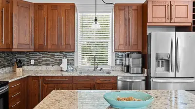 a kitchen with wooden cabinets and a bowl on a counter at Serene 30A Getaway Steps from the Gulf with BBQ Wraparound Porch 30A Fade Away by AvantStay in Santa Rosa Beach