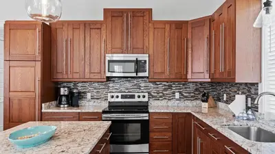 a kitchen with wooden cabinets and a stove top oven at Serene 30A Getaway Steps from the Gulf with BBQ Wraparound Porch 30A Fade Away by AvantStay in Santa Rosa Beach