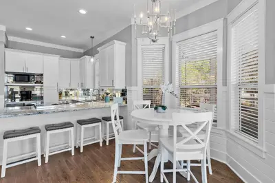 a white kitchen with a table and white chairs at Geauxing Coastal 10 ppl 3 BR 3BA Bikes Community pool 5 Min walk to the beach in Seacrest