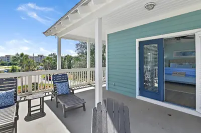 a blue house with two chairs and a bed on a porch at Geauxing Coastal 10 ppl 3 BR 3BA Bikes Community pool 5 Min walk to the beach in Seacrest