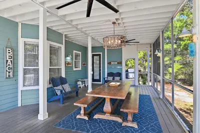 a porch with a wooden table and a chandelier at Geauxing Coastal 10 ppl 3 BR 3BA Bikes Community pool 5 Min walk to the beach in Seacrest