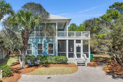 a blue house with a porch and a palm tree at Geauxing Coastal 10 ppl 3 BR 3BA Bikes Community pool 5 Min walk to the beach in Seacrest