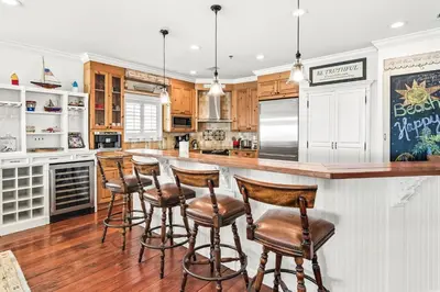 a kitchen with wooden cabinets and a bar with stools at 4 BR GULF Front Condo, Bikes, & Community Pool in Seagrove Beach