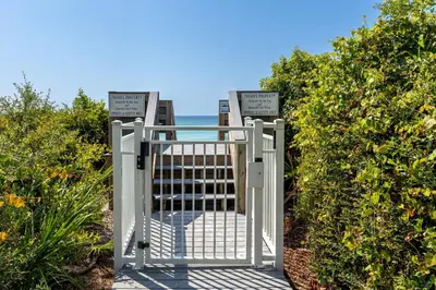 a gate to the beach with the ocean behind it at 4 BR GULF Front Condo, Bikes, & Community Pool in Seagrove Beach