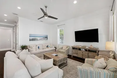 a living room with white furniture and a flat screen tv at NEW! Fall Break OPEN 4 BR, Pool, Bikes & close to shopping & beach in Seagrove Beach