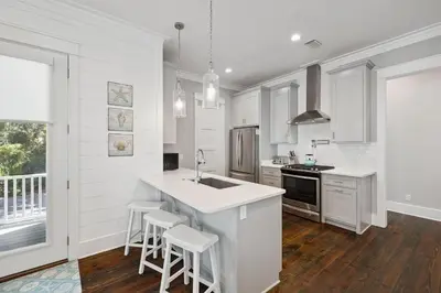 a white kitchen with a counter and stools in it at NEW! Fall Break OPEN 4 BR, Pool, Bikes & close to shopping & beach in Seagrove Beach