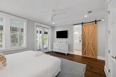 a white bedroom with a bed and a television at NEW! Fall Break OPEN 4 BR, Pool, Bikes & close to shopping & beach in Seagrove Beach