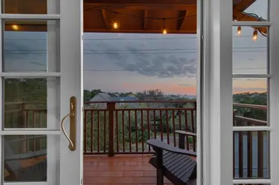 a door to a balcony with a view of the sunset at 30a Seagrove Beach Condo with Gulf & Lake Views in Santa Rosa Beach
