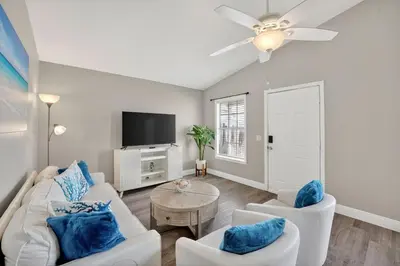 a living room with white furniture and a flat screen tv at Luxury Beach Access in Panama City Beach