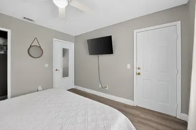 a white bedroom with a bed and a flat screen tv at Luxury Beach Access in Panama City Beach