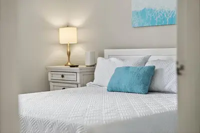 a bedroom with a white bed with a blue pillow at Luxury Beach Access in Panama City Beach