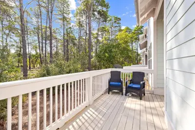 a balcony with two chairs and a view of the woods at 30A All Day 88 E Pine Lands Loop Unit A in Inlet Beach