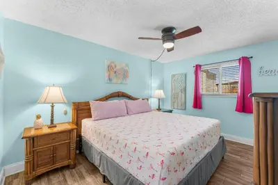a bedroom with a bed and a ceiling fan at Turtle Cove at Sugar Beach #E16 by Nautical Properties Vacation Rentals in Panama City Beach