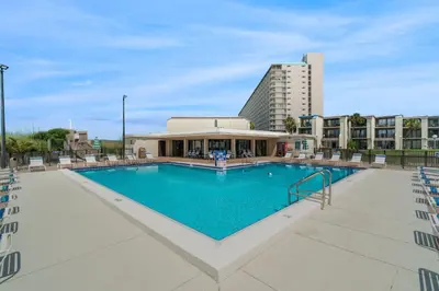 a large swimming pool with chairs and a building at Turtle Cove at Sugar Beach #E16 by Nautical Properties Vacation Rentals in Panama City Beach
