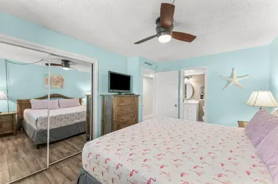 a bedroom with a bed and a flat screen tv at Turtle Cove at Sugar Beach #E16 by Nautical Properties Vacation Rentals in Panama City Beach