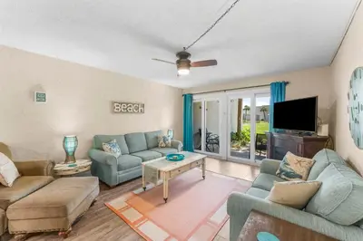 a living room with two couches and a tv at Turtle Cove at Sugar Beach #E16 by Nautical Properties Vacation Rentals in Panama City Beach