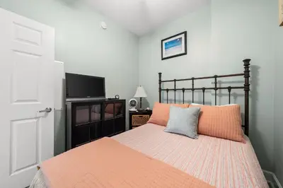 a bedroom with a bed with orange sheets and a tv at Music City Flamingo at Sunrise Beach Resort #705 by Nautical Properties in Panama City Beach