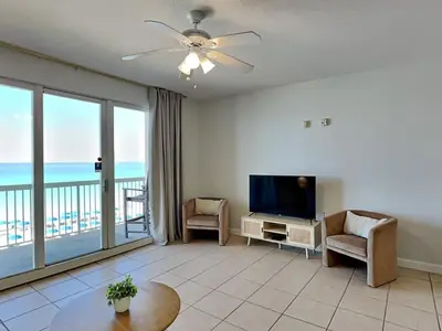 a living room with a television and a balcony at Seychelles #402 in Panama City Beach