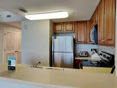 a kitchen with a stainless steel refrigerator and wooden cabinets at Seychelles #402 in Panama City Beach