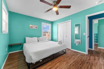 a bed in a blue room with a ceiling fan at Sunset Ave Beach House - Golf Cart, Pool, Hot Tub in Panama City Beach