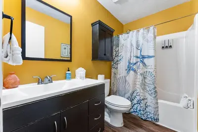 a bathroom with a sink and a toilet and a shower curtain at Sunset Ave Beach House - Golf Cart, Pool, Hot Tub in Panama City Beach