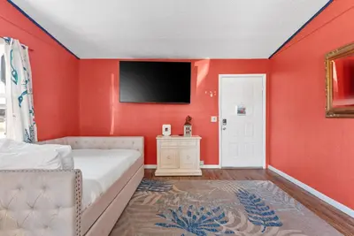 a bedroom with red walls and a bed and a tv at Sunset Ave Beach House - Golf Cart, Pool, Hot Tub in Panama City Beach
