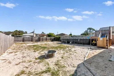 a dirt yard with a fence and a wooden fence at Sunset Ave Beach House - Golf Cart, Pool, Hot Tub in Panama City Beach