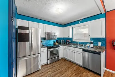 a kitchen with white cabinets and blue walls at Sunset Ave Beach House - Golf Cart, Pool, Hot Tub in Panama City Beach