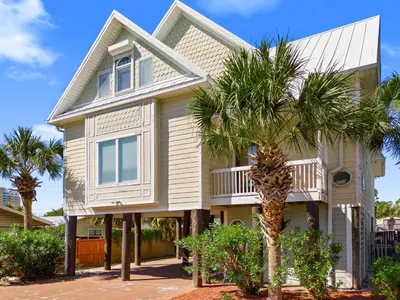 a house with a palm tree in front of it at Lazy River Retreat in Panama City Beach