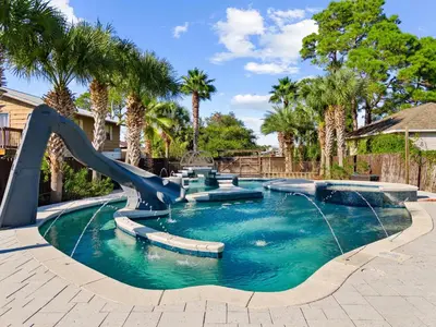 a water slide in a pool with palm trees at Lazy River Retreat in Panama City Beach