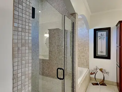 a bathroom with a glass shower with a tub and a sink at Lazy River Retreat in Panama City Beach