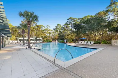 a swimming pool with chairs and a palm tree at Sea D’Light: 3BR Beach Home Sleeps 10 with 4 Bikes in Watersound West in Santa Rosa Beach