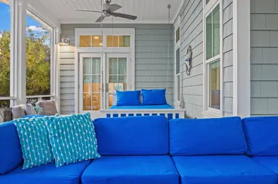 a blue couch on a screened porch with blue pillows at Sea D’Light: 3BR Beach Home Sleeps 10 with 4 Bikes in Watersound West in Santa Rosa Beach