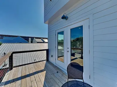 a house with two chairs on a deck with a door at Sunset on Snapper C in Panama City Beach