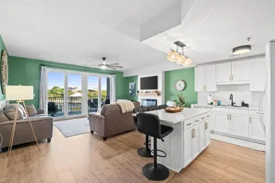 a kitchen and living room with green walls at Relaxing 2nd-Floor Laketown Wharf Condo Overlooking the Lake in Panama City Beach
