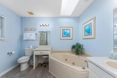 a blue bathroom with a tub and a toilet and a sink at Walk to Emerald Beach,Cozy Coastal Getaway in Panama City Beach