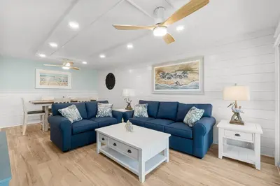 a living room with a blue couch and a table at Charming Beachfront Condo with Stunning Views in Panama City Beach