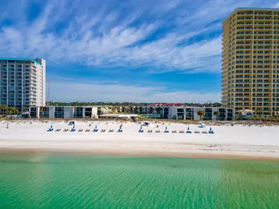 a beach with beach chairs and buildings and the water at Charming Beachfront Condo with Stunning Views in Panama City Beach