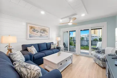 a living room with a blue couch and a table at Charming Beachfront Condo with Stunning Views in Panama City Beach