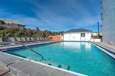 a swimming pool with chairs and blue water at Book Me Baby! License to Chill One Seagrove Place in Seagrove Beach