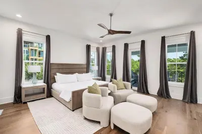 a bedroom with a bed and chairs and windows at Oz by The Sea in Inlet Beach