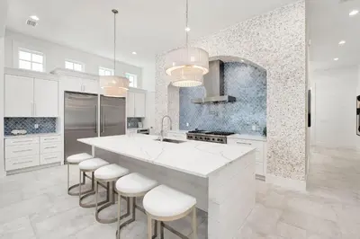 a kitchen with white cabinets and a large island with stools at Oz by The Sea in Inlet Beach