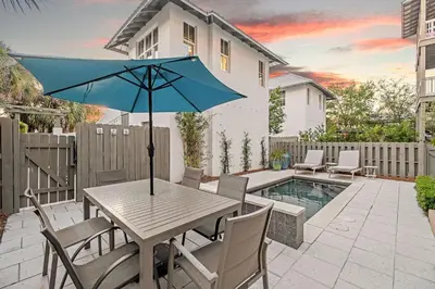 a wooden table with a blue umbrella on a patio at North Winston Villa in Inlet Beach