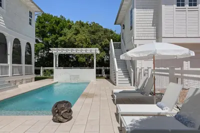 a swimming pool with two lounge chairs and an umbrella at Traveler's Rest in Inlet Beach
