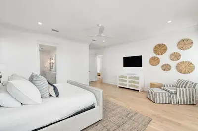 a white bedroom with a bed and a chair at Marisol 30A in Inlet Beach