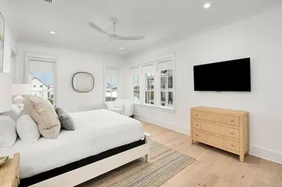 a white bedroom with a bed and a flat screen tv at Marisol 30A in Inlet Beach